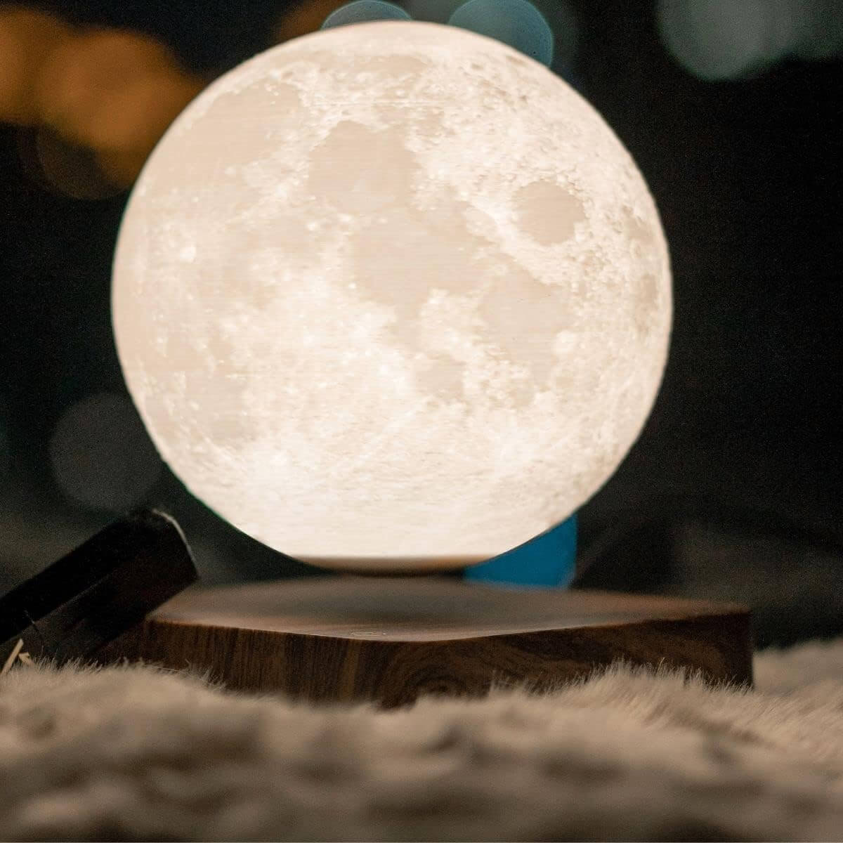 3D-Printed Levitating Moon Lamp illuminated on a wooden base over a soft, cozy surface