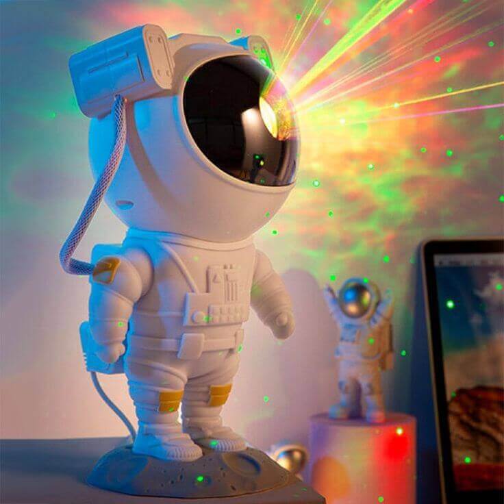 Astronaut lighting galaxy projector illuminating a room with colorful starry night effects.