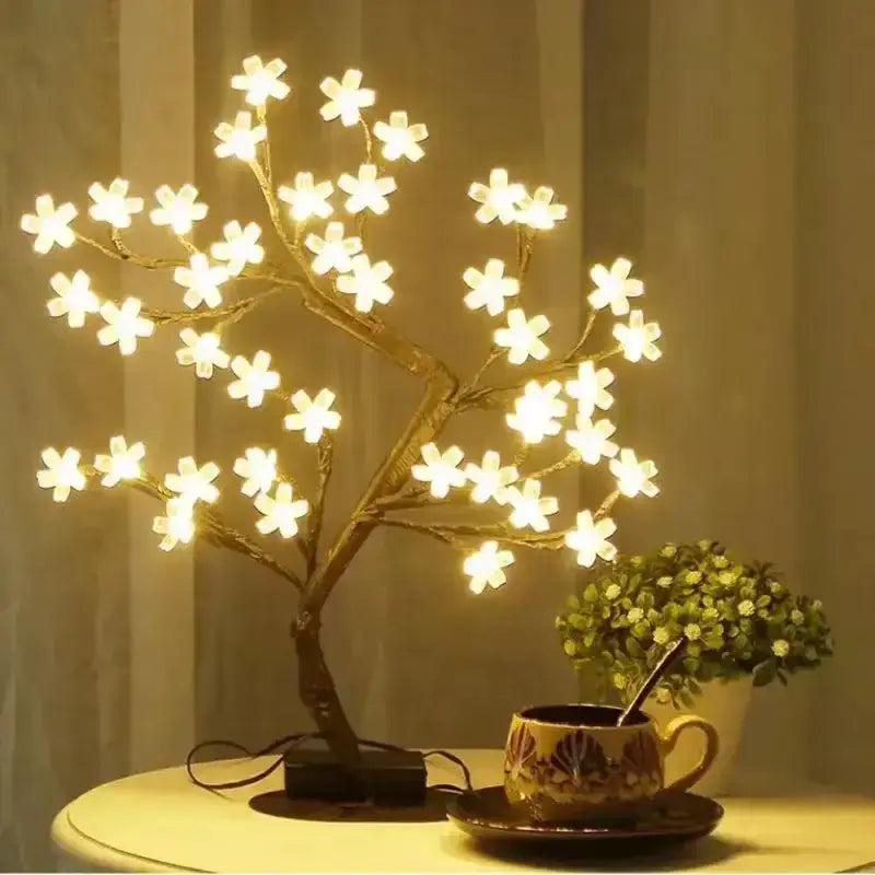 Illuminated Sakura Flower Lamp with cherry blossom design on a table next to a tea cup and a small plant for home decor elegance.