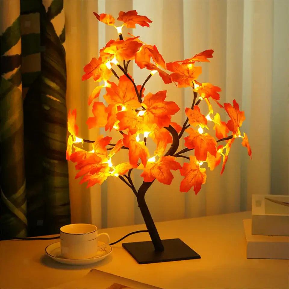 Bonsai-style Maple Leaf Lamp with LED lights illuminating autumn-colored leaves, enhancing a cozy living space on a wooden table.